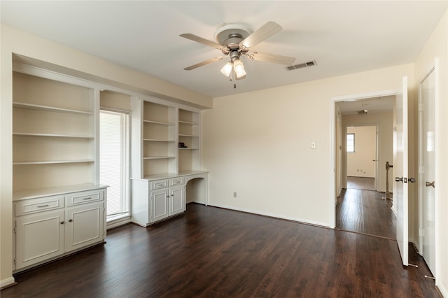 interior space featuring dark wood-style floors, a ceiling fan, visible vents, and a wealth of natural light