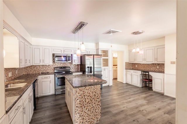 kitchen with dark wood finished floors, stainless steel appliances, visible vents, decorative backsplash, and a kitchen island