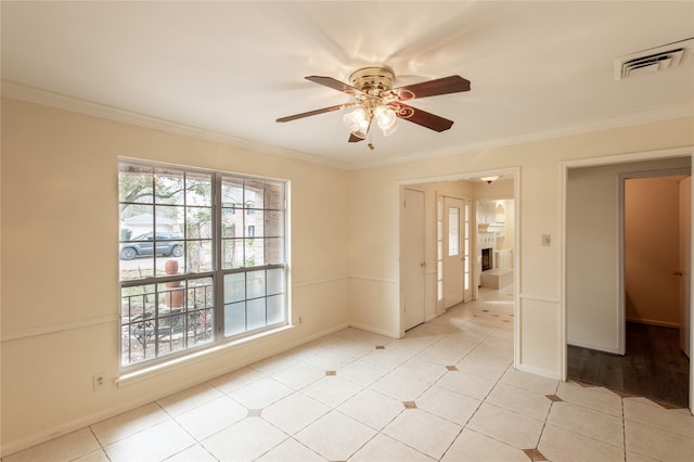 spare room with ornamental molding, visible vents, and a ceiling fan