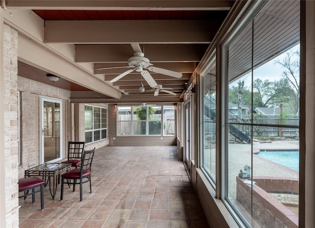 unfurnished sunroom with ceiling fan and beam ceiling