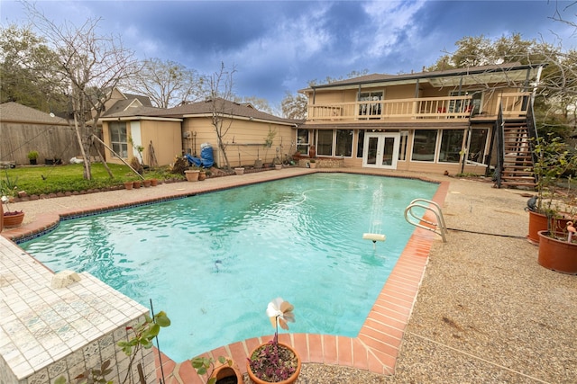 view of pool with a fenced in pool, french doors, a patio area, and stairs