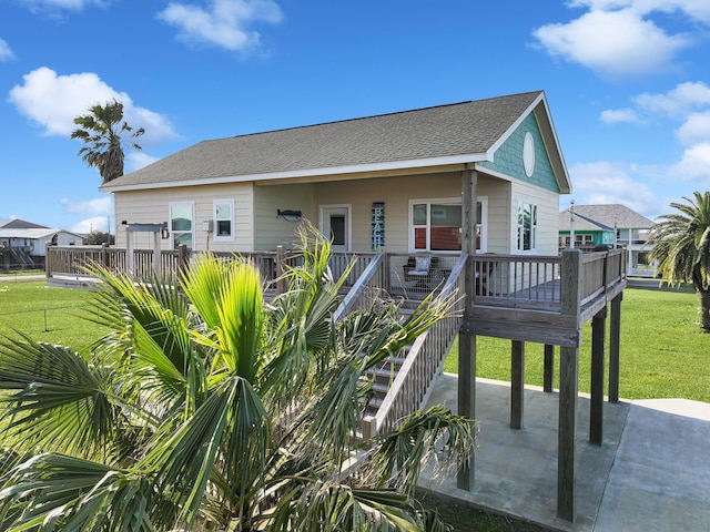 rear view of house with roof with shingles, a patio, and a yard