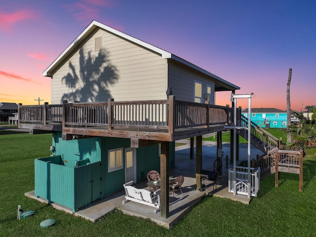 back of house at dusk featuring a patio area, a yard, a wooden deck, and stairs