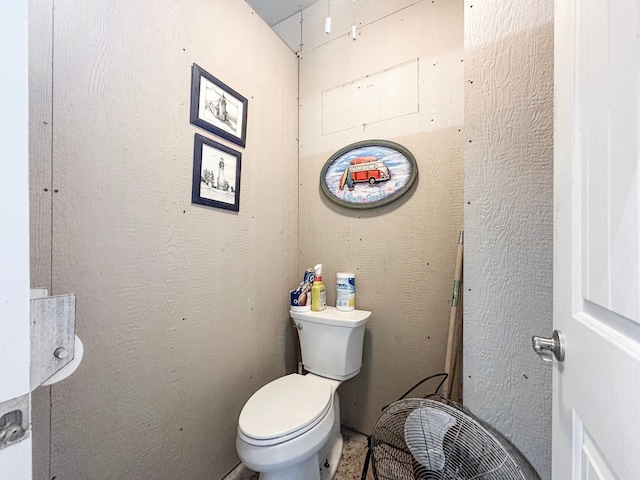 bathroom featuring a textured wall and toilet