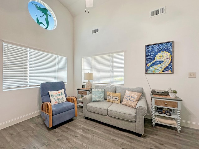 living area featuring high vaulted ceiling, baseboards, visible vents, and wood finished floors