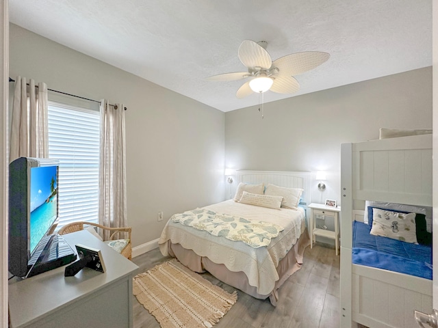 bedroom with light wood-style flooring, baseboards, ceiling fan, and a textured ceiling