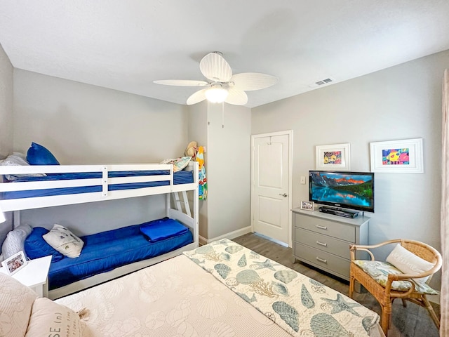 bedroom featuring ceiling fan, wood finished floors, visible vents, and baseboards