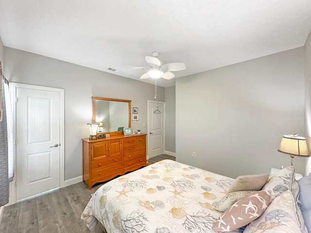 bedroom featuring ceiling fan, wood finished floors, visible vents, and baseboards