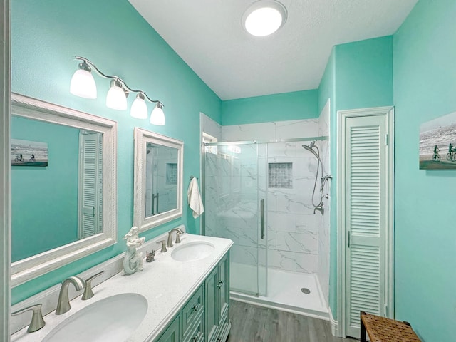 full bath with wood finished floors, a sink, and a marble finish shower