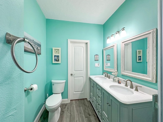 full bath with baseboards, a sink, toilet, and wood finished floors