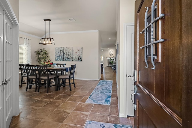 interior space featuring ornamental molding, dark tile patterned flooring, visible vents, and baseboards