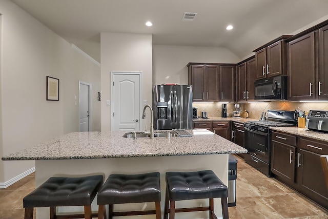 kitchen with decorative backsplash, a kitchen breakfast bar, a sink, and black appliances