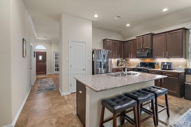 kitchen featuring black microwave, dark brown cabinetry, backsplash, stainless steel fridge with ice dispenser, and range with gas cooktop