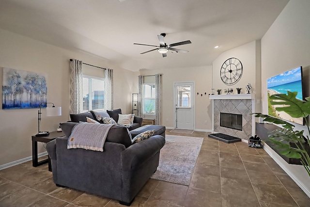 living area featuring lofted ceiling, baseboards, ceiling fan, and a tiled fireplace