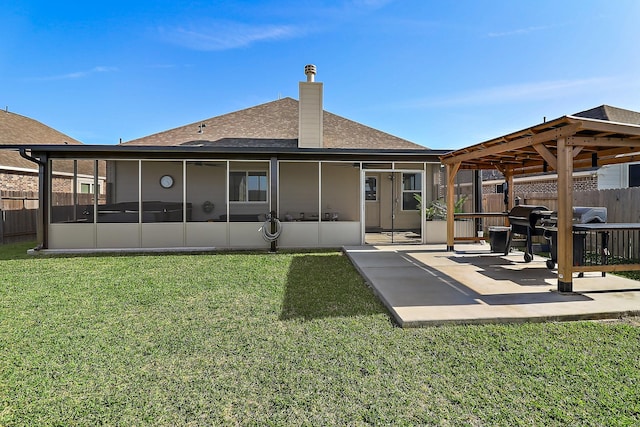 back of house featuring roof with shingles, a yard, a patio, a sunroom, and fence