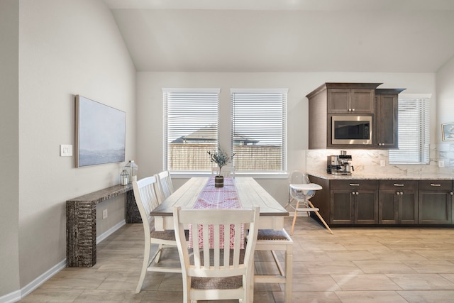 dining space with a healthy amount of sunlight, vaulted ceiling, and baseboards