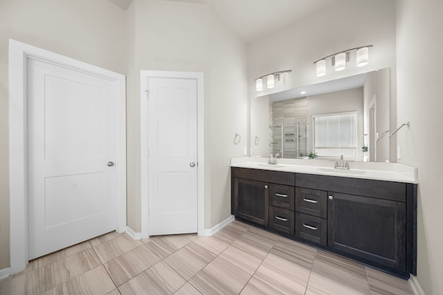 full bath featuring a sink, a shower stall, baseboards, and double vanity