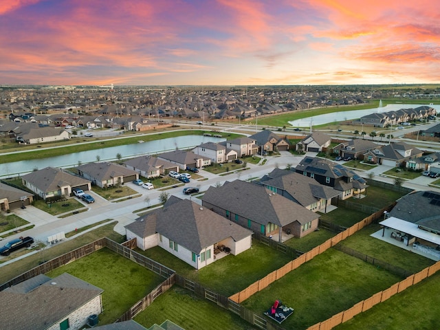 aerial view at dusk featuring a residential view and a water view