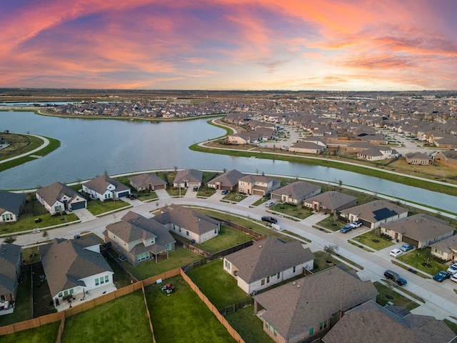 aerial view at dusk with a residential view and a water view