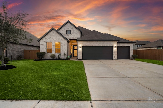 view of front of home with a garage, brick siding, fence, a yard, and driveway