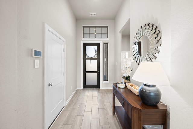 foyer with wood finish floors, visible vents, and baseboards