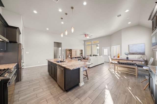 kitchen with light stone counters, a sink, visible vents, appliances with stainless steel finishes, and a kitchen bar