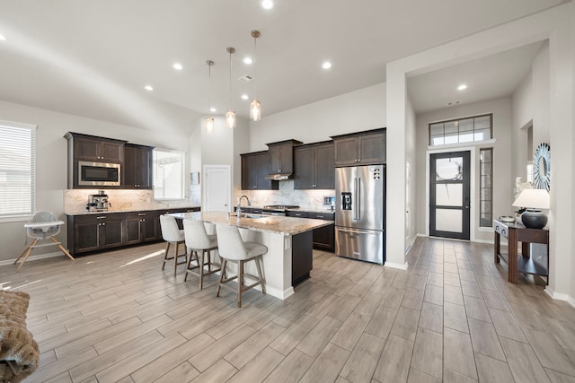 kitchen featuring stainless steel appliances, dark brown cabinets, a sink, and tasteful backsplash