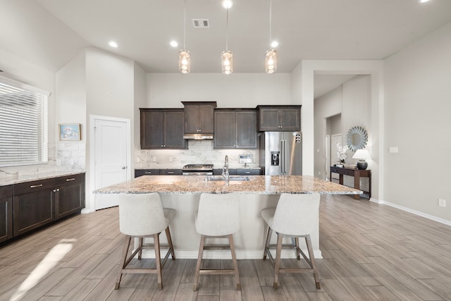 kitchen with dark brown cabinets, a kitchen bar, stainless steel appliances, and a sink