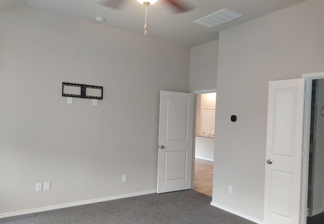 unfurnished bedroom featuring dark colored carpet, visible vents, a ceiling fan, high vaulted ceiling, and baseboards