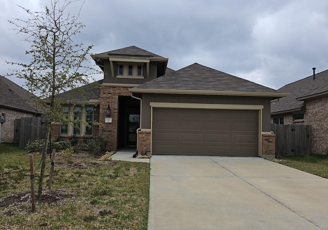 prairie-style home with an attached garage, fence, concrete driveway, and brick siding