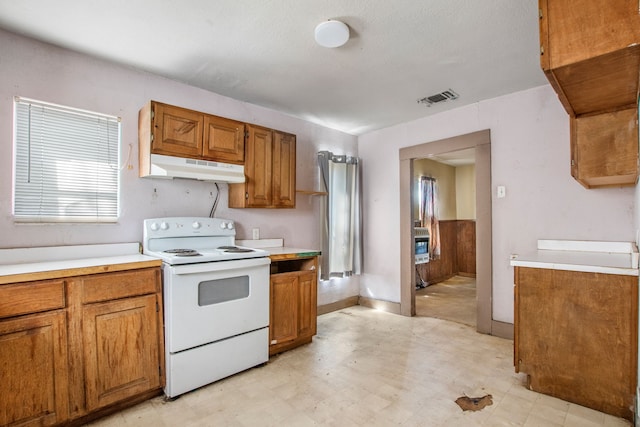 kitchen featuring brown cabinets, light floors, light countertops, white electric range, and under cabinet range hood