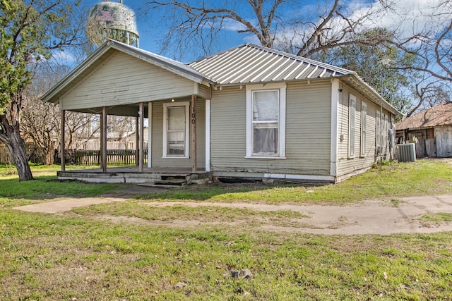 view of front of home with covered porch, metal roof, central AC unit, and a front yard