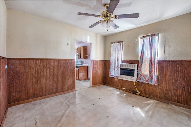 unfurnished room featuring wood walls, wainscoting, tile patterned floors, and heating unit