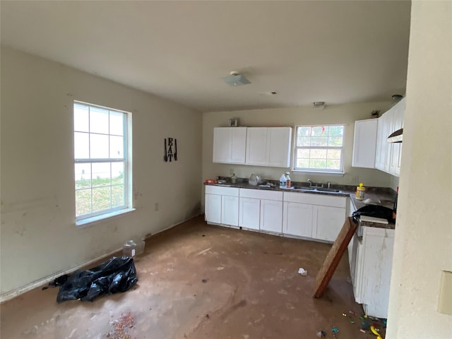 kitchen featuring dark countertops, white cabinets, a sink, range, and under cabinet range hood