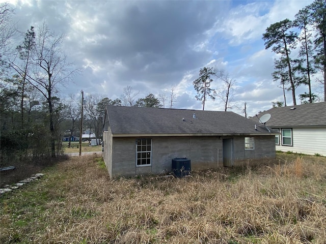 rear view of property with a shingled roof and cooling unit