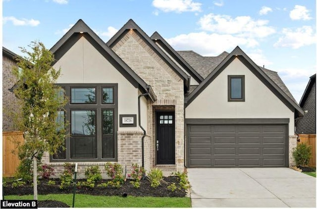 view of front facade with stone siding, fence, driveway, and stucco siding