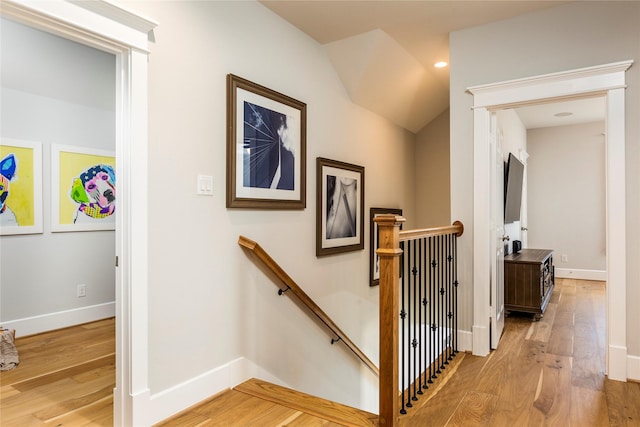 hallway featuring light wood-type flooring, baseboards, and an upstairs landing