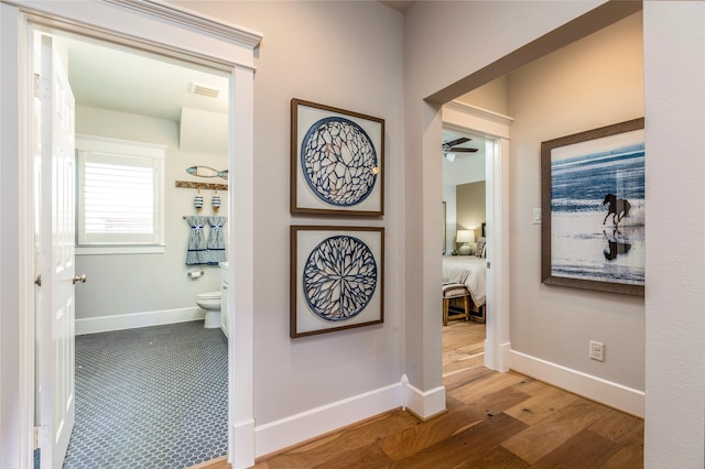 corridor with visible vents, baseboards, and wood finished floors