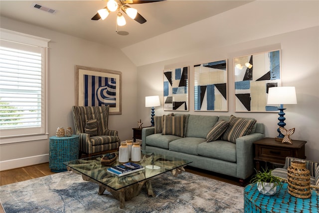 living area with lofted ceiling, visible vents, a ceiling fan, wood finished floors, and baseboards