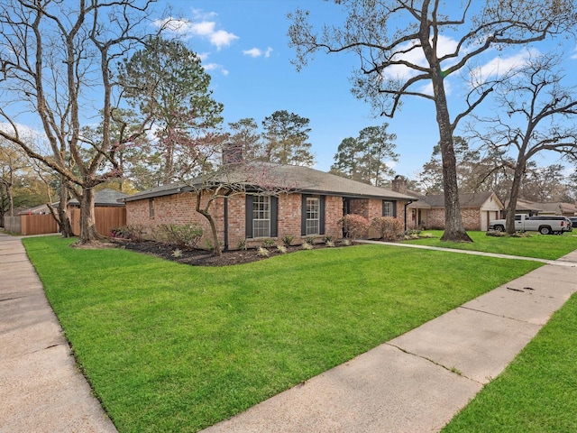 view of front of home featuring a front yard, brick siding, a chimney, and fence