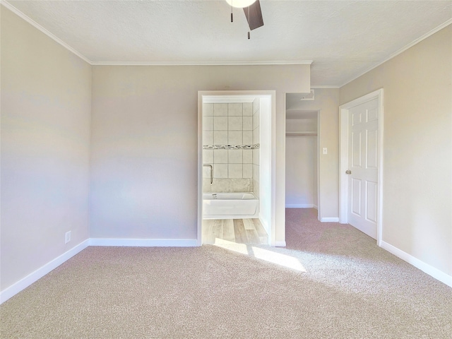 unfurnished bedroom featuring carpet, crown molding, and baseboards