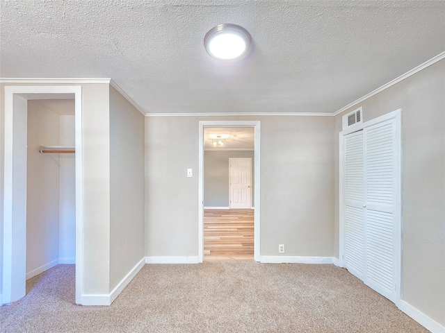 unfurnished bedroom featuring carpet, a closet, visible vents, ornamental molding, and baseboards