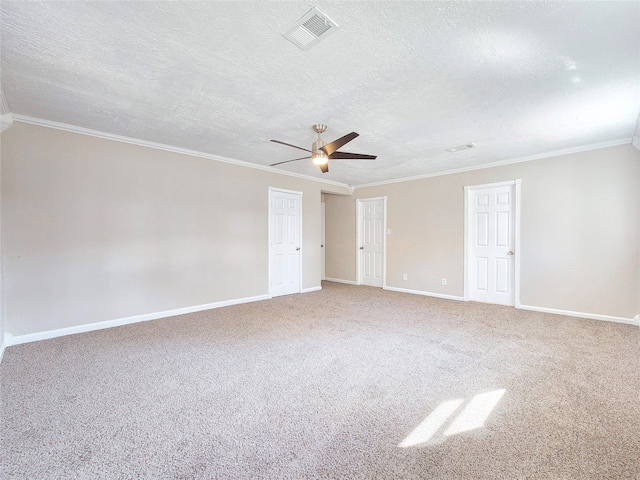 empty room with a textured ceiling, carpet flooring, visible vents, baseboards, and ornamental molding