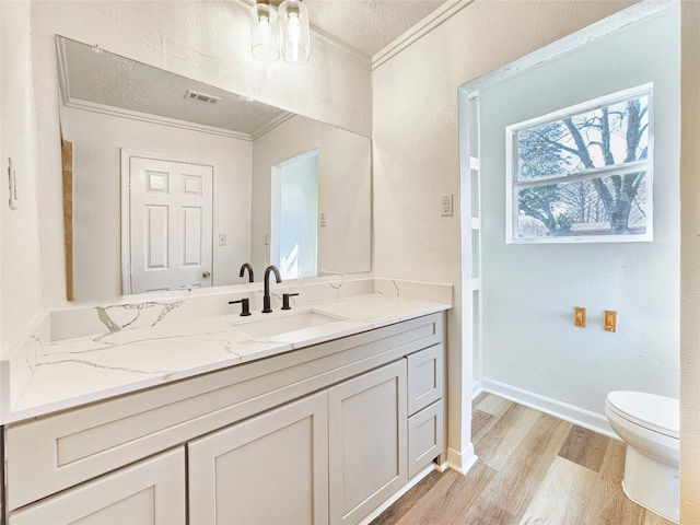 bathroom with crown molding, toilet, vanity, wood finished floors, and baseboards