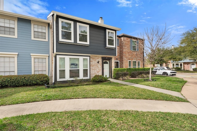 townhome / multi-family property featuring brick siding, a front lawn, and a chimney