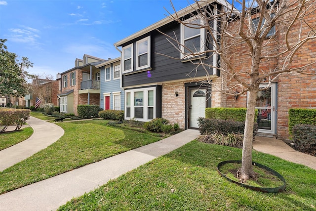 townhome / multi-family property with brick siding, a front lawn, and a residential view