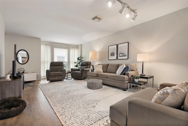 living area with hardwood / wood-style flooring, visible vents, and track lighting