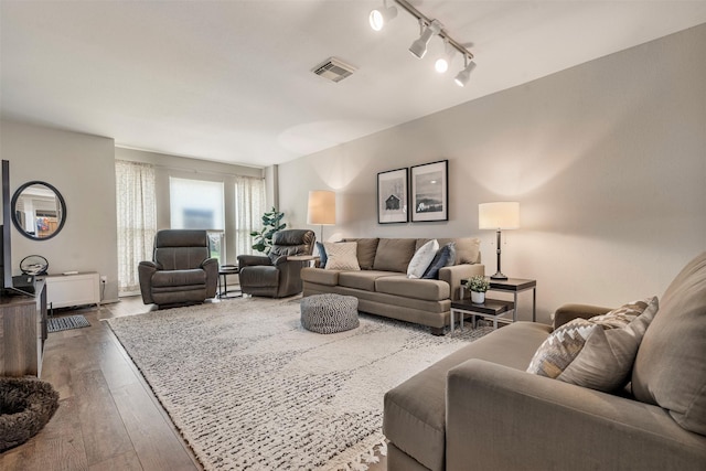 living room featuring rail lighting, visible vents, and wood finished floors