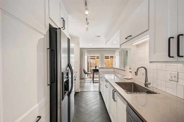 kitchen featuring visible vents, white cabinets, stainless steel fridge with ice dispenser, a sink, and backsplash