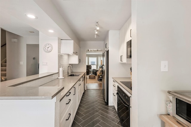 kitchen featuring a sink, white cabinets, light countertops, decorative backsplash, and black appliances